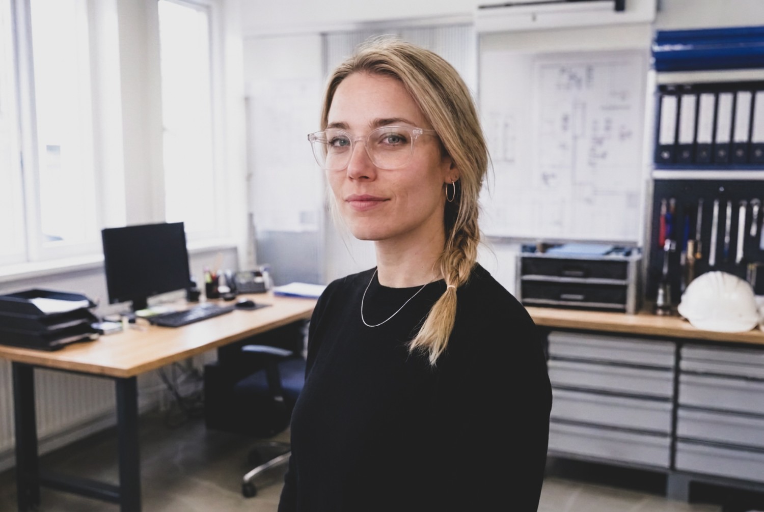 Ingenieurin steht im Büro mit technischen Zeichnungen