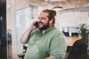 Mitarbeiter im Marketing telefoniert lachend im Büro